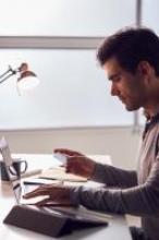 This is a man at a computer holding a credit card. 