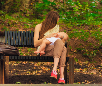 Parent nursing infant on a park bench