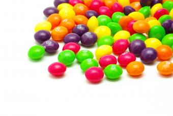 Skittles in a pile on a white background.