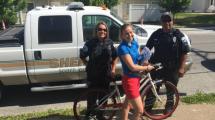 Police officers with a girl on a bike.